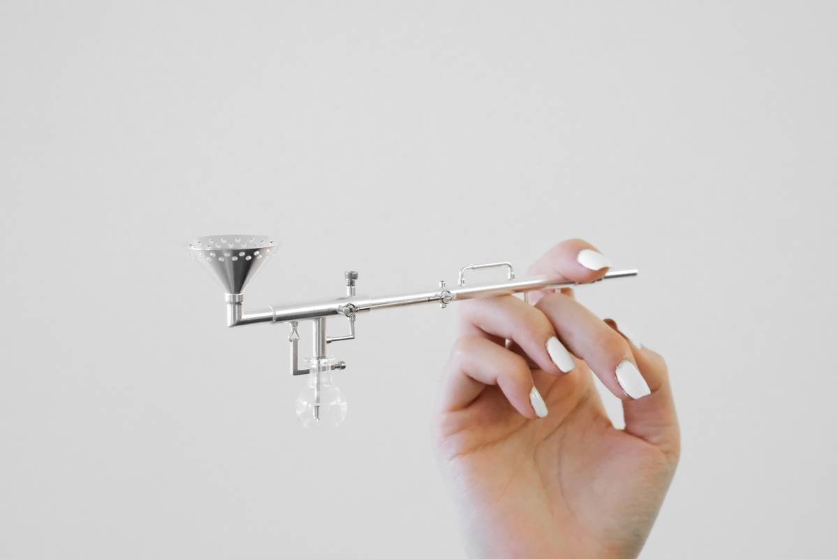 Close-up of a professional using a nail art filer tool on an acrylic nail with proper hand positioning
